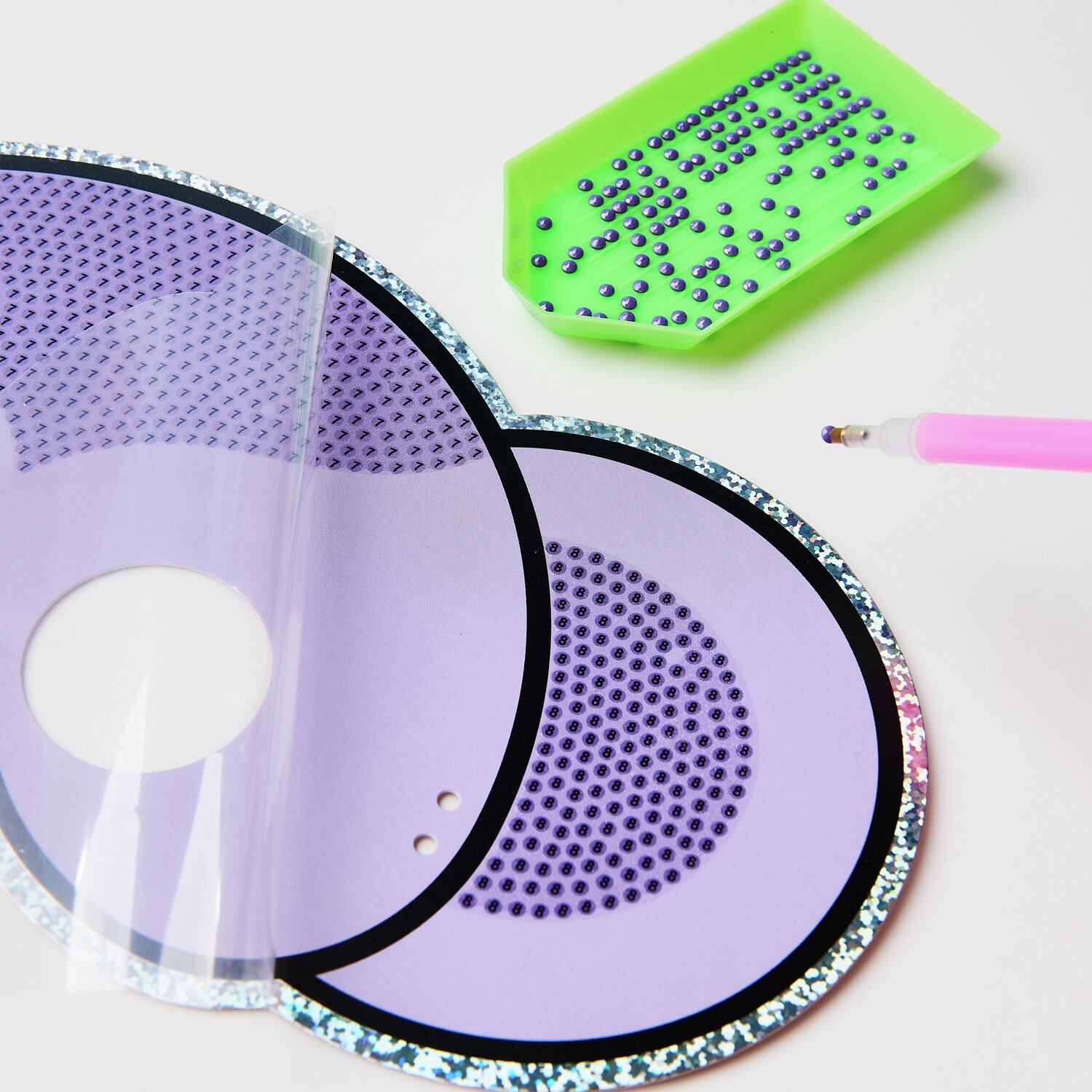 Diamond Painting Masken Tiere, 52-teilig. Lila Maske mit grüner Schale und pinkem Stift.