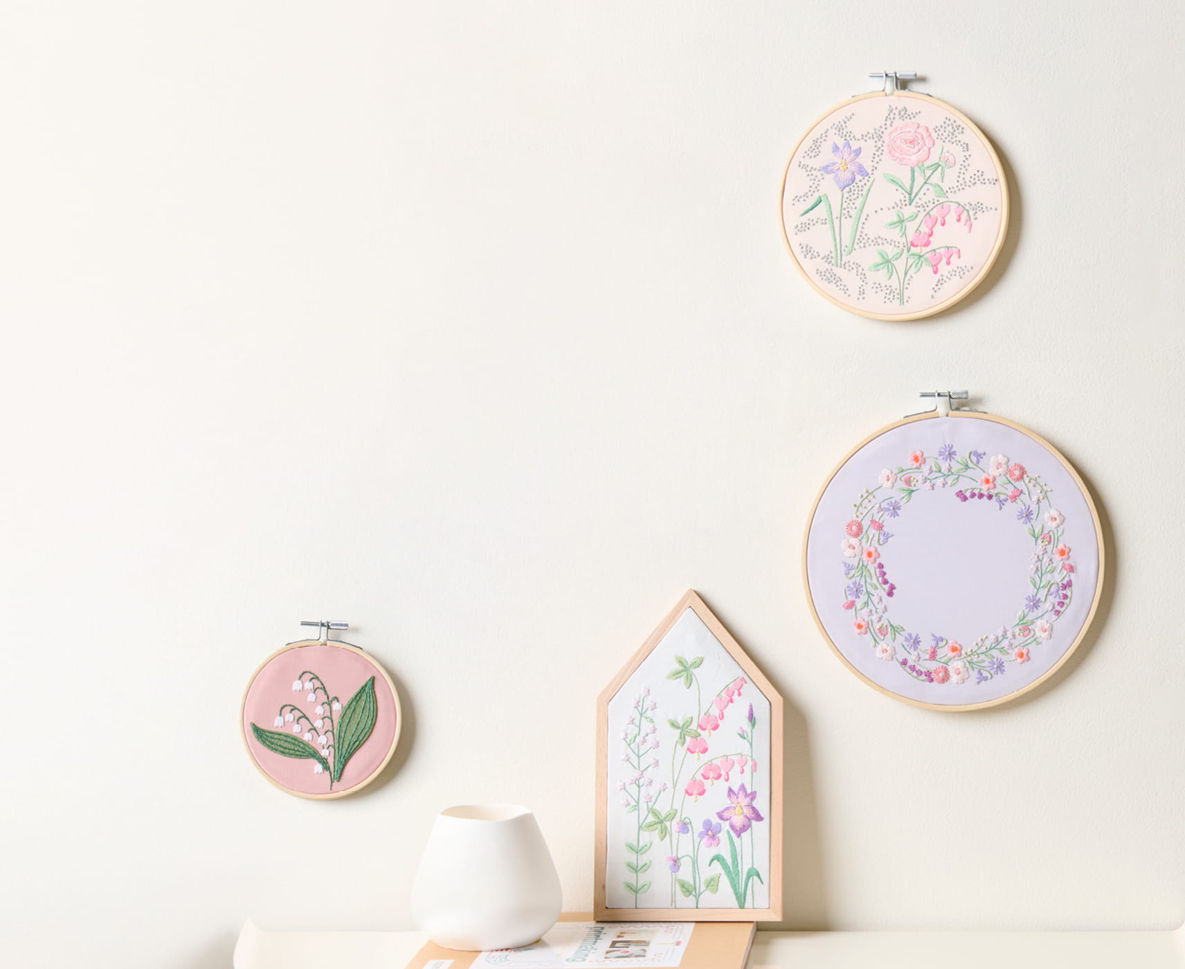 Stickbilder mit floralen Stickdesigns aus der Kollektion The Sky is the Limit hängen an einer Wand.