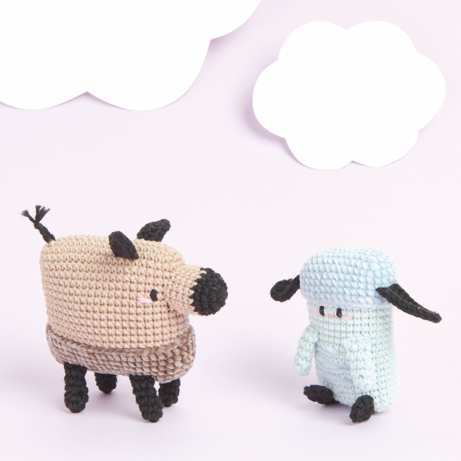 Ricorumi Rainbow Weirdos, zwei gehäkelte Figuren in Hellblau und Beige mit schwarzen Details vor wolkigem Hintergrund.